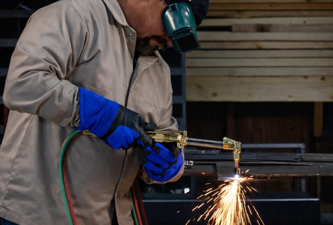 Operator cutting steel with an oxy-acetylene torch in a workshop