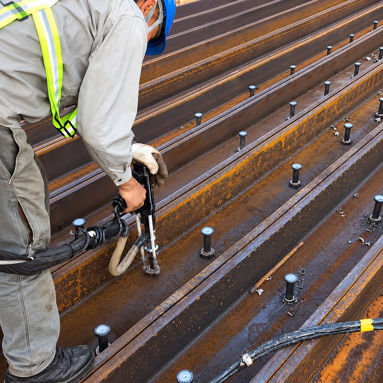 Operator welding shear connectors on composite deck beams